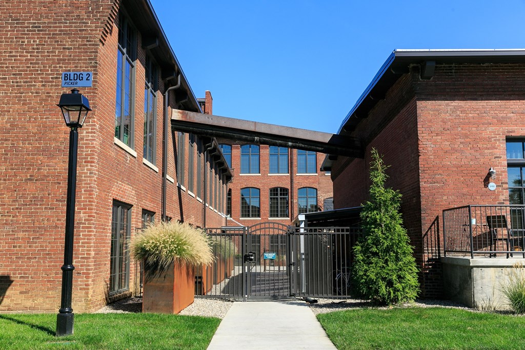 the front of a brick building with a sidewalk and a gate