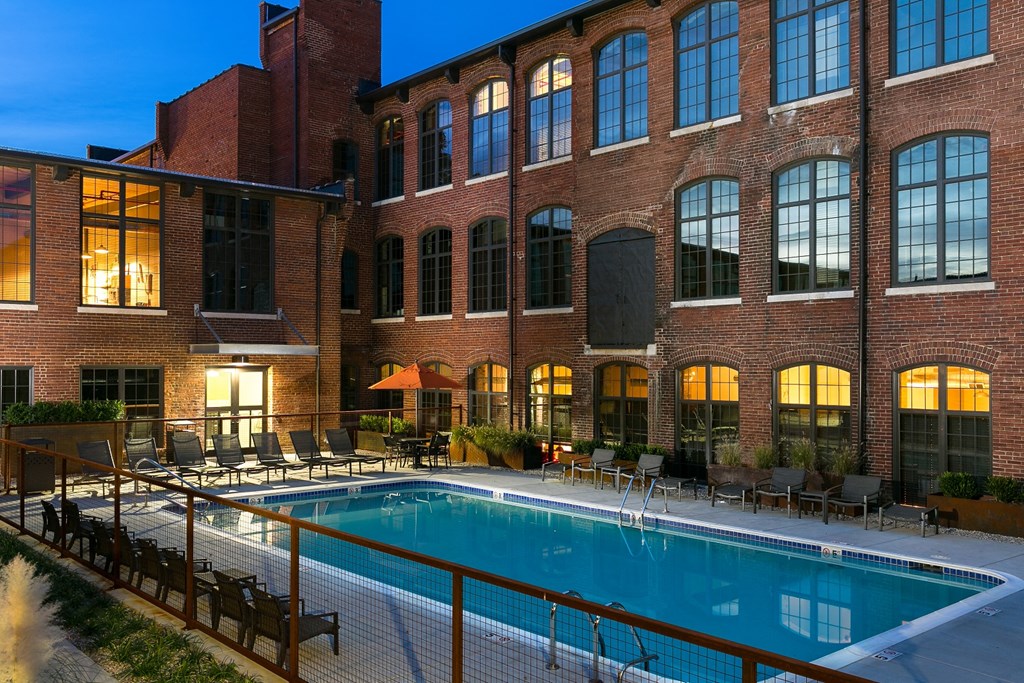 a swimming pool at night in front of a brick building