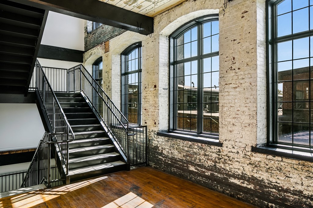 the exposed brick facade of a building with a staircase and large windows