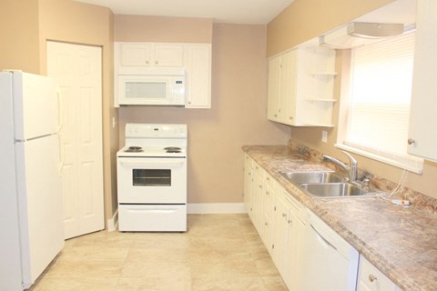 A kitchen with a white refrigerator, white oven, and white cabinets.
