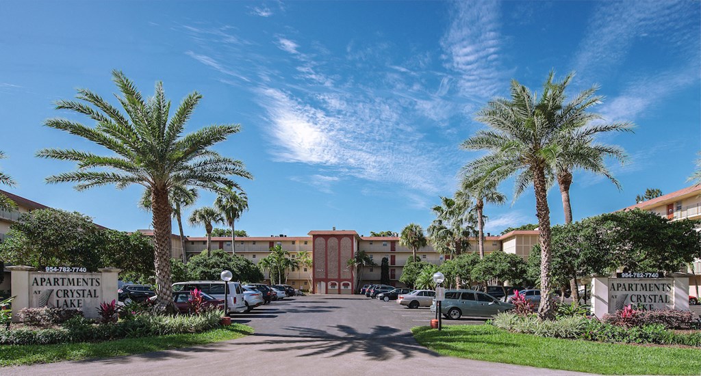 a parking lot with palm trees in front of a building