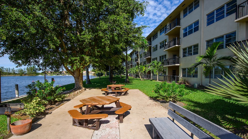 a park with benches and picnic tables next to an apartment building
