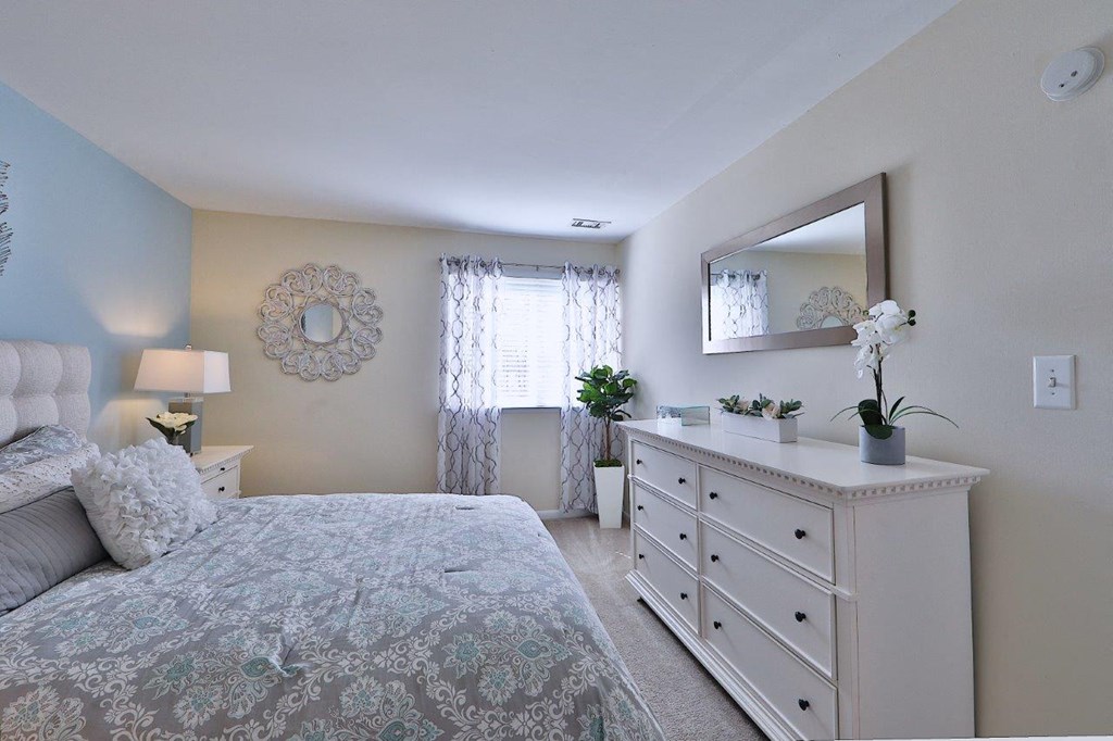 a bedroom with a bed and dresser and a mirror