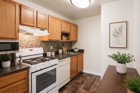 A kitchen with a white stove top oven and wooden cabinets.
