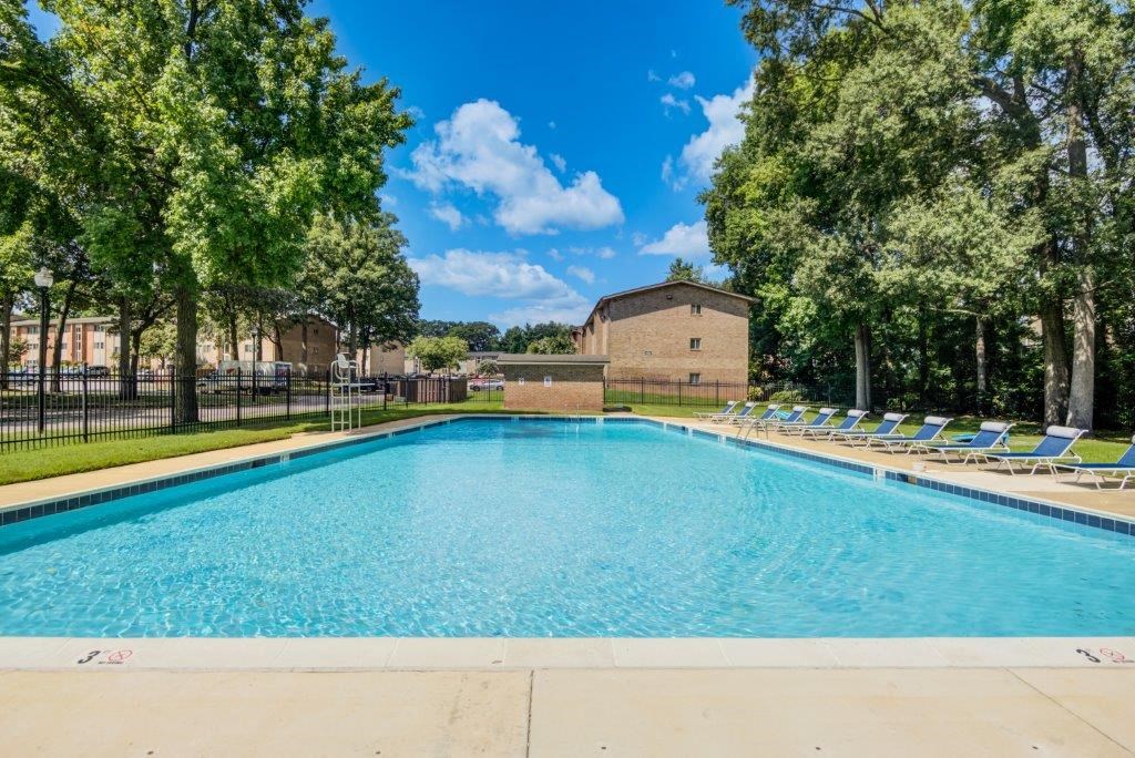 a swimming pool with chairs around it and a building in the background