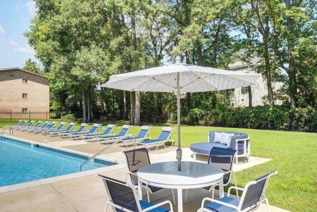 a swimming pool with blue and white chairs and a table and umbrella