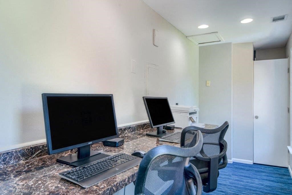 a office with three computer monitors and a keyboard on a desk