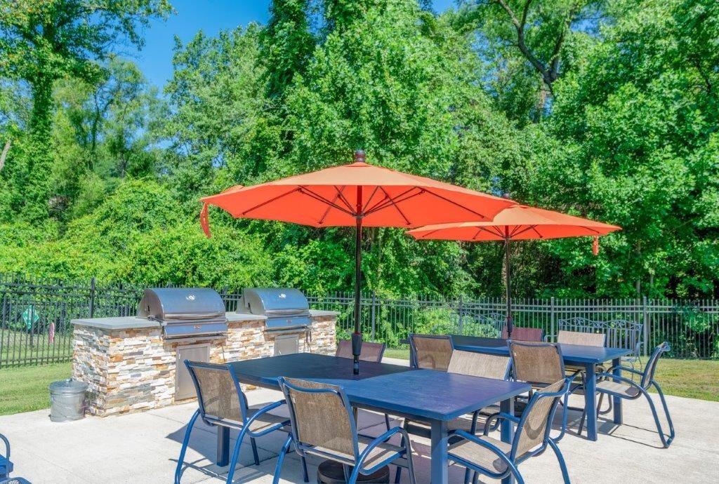 a patio with tables and chairs and an orange umbrella