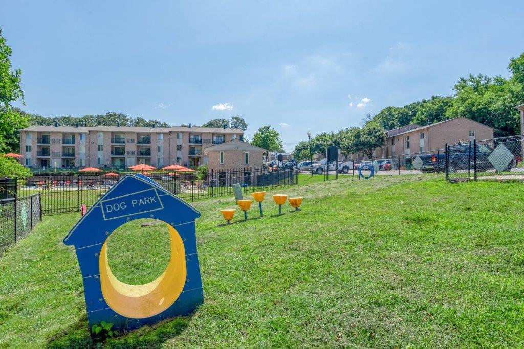 a dog park with benches and apartments in the background