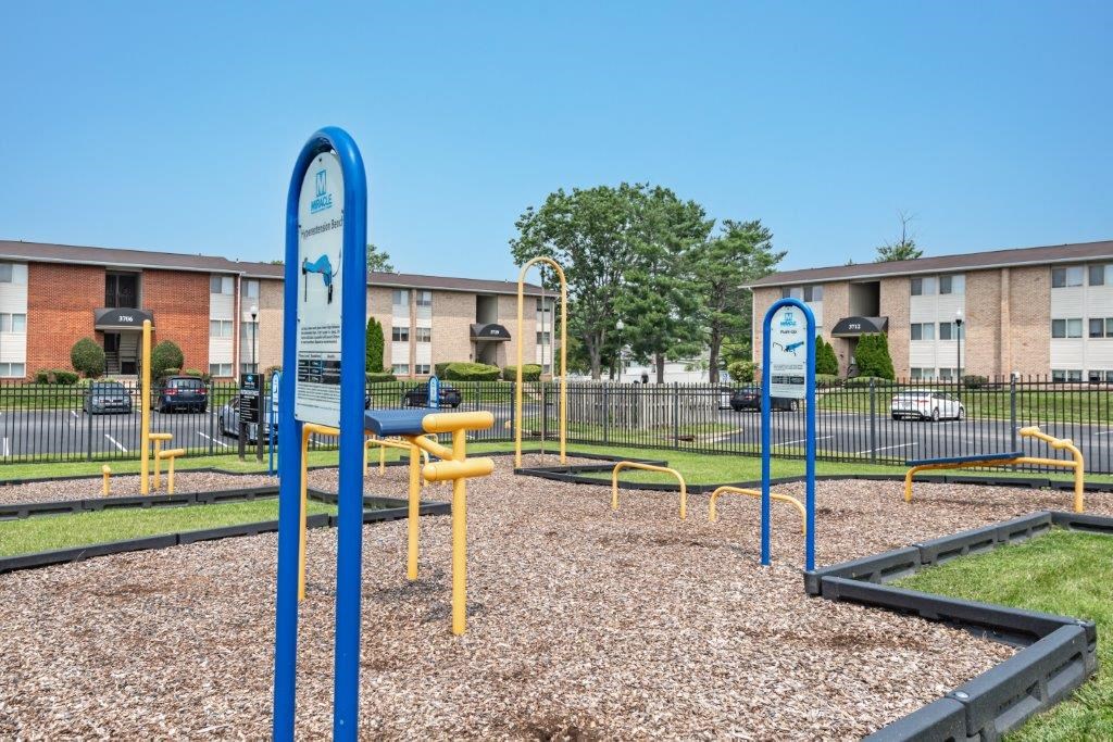 a playground with blue and yellow equipment in front of an apartment building