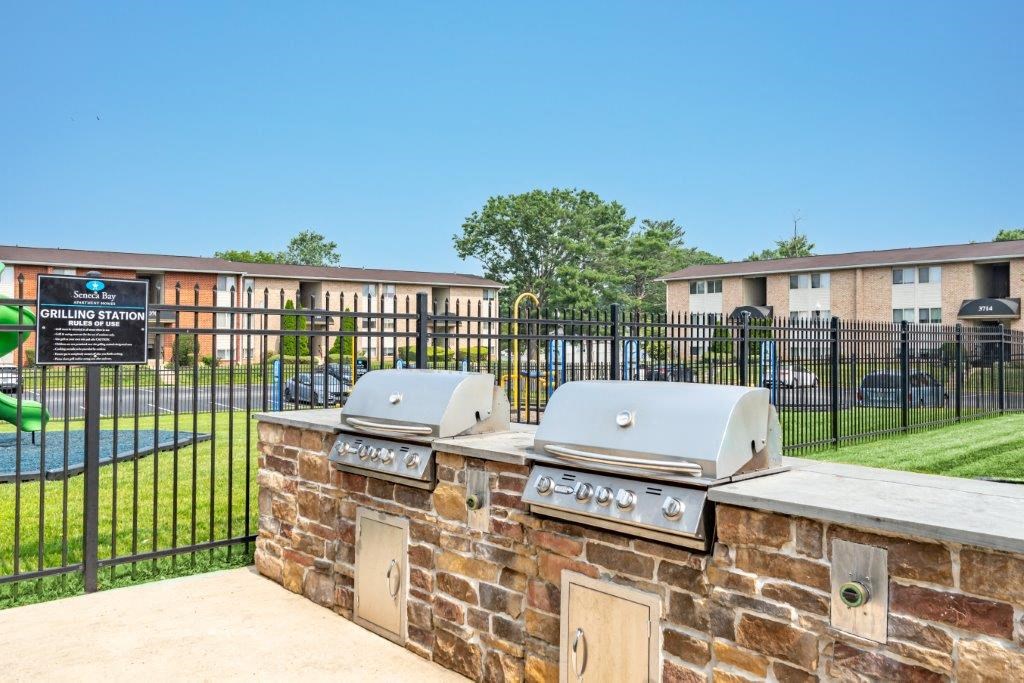 an outdoor grill with two bbqs in front of a building