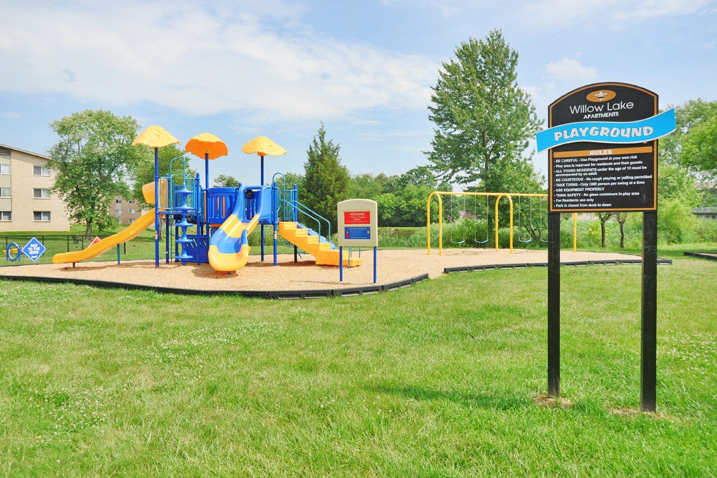a playground in a park with a sign for the play ground