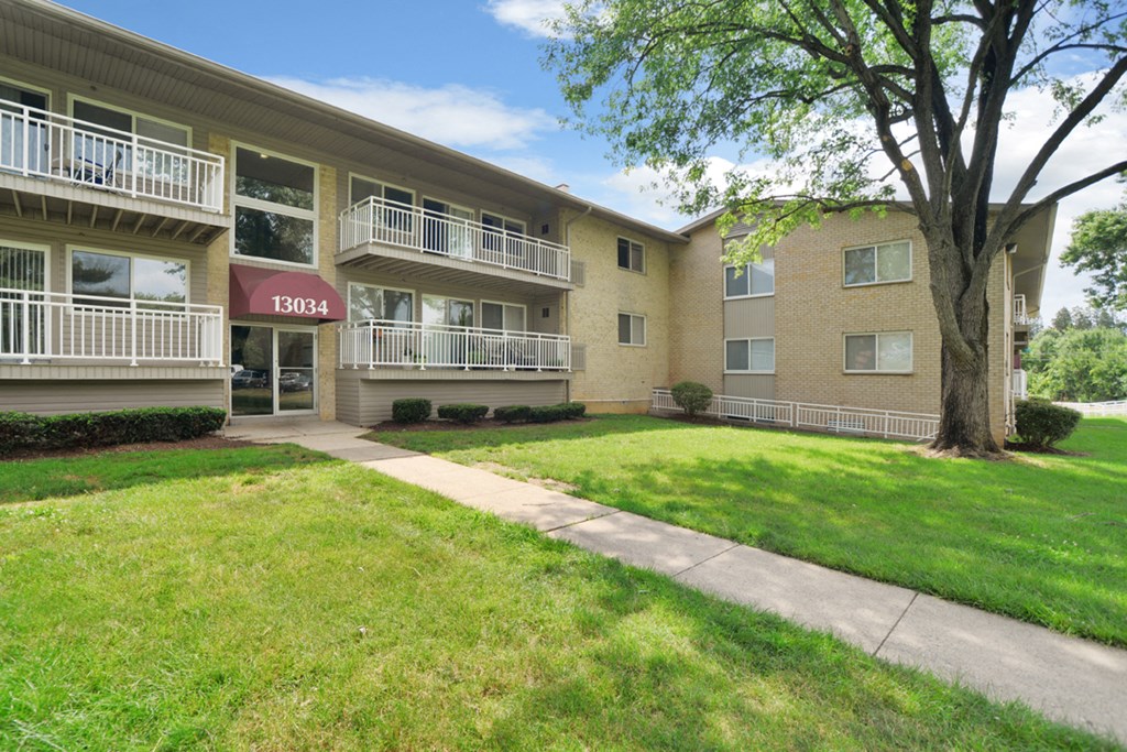 an exterior view of an apartment building with a sidewalk and grass