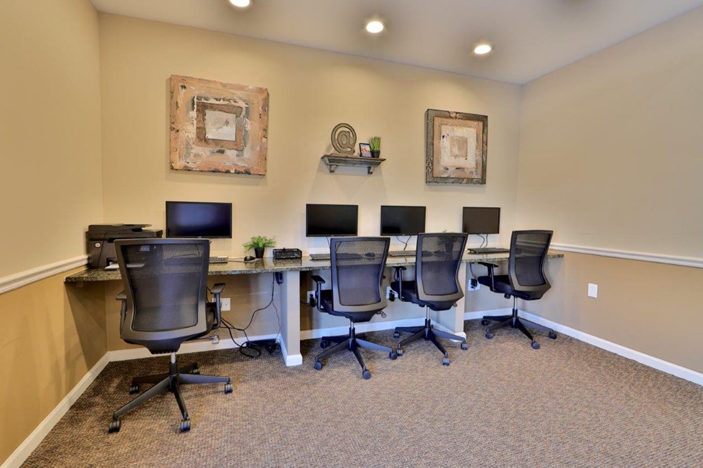 a group of desks with computers and chairs in a room