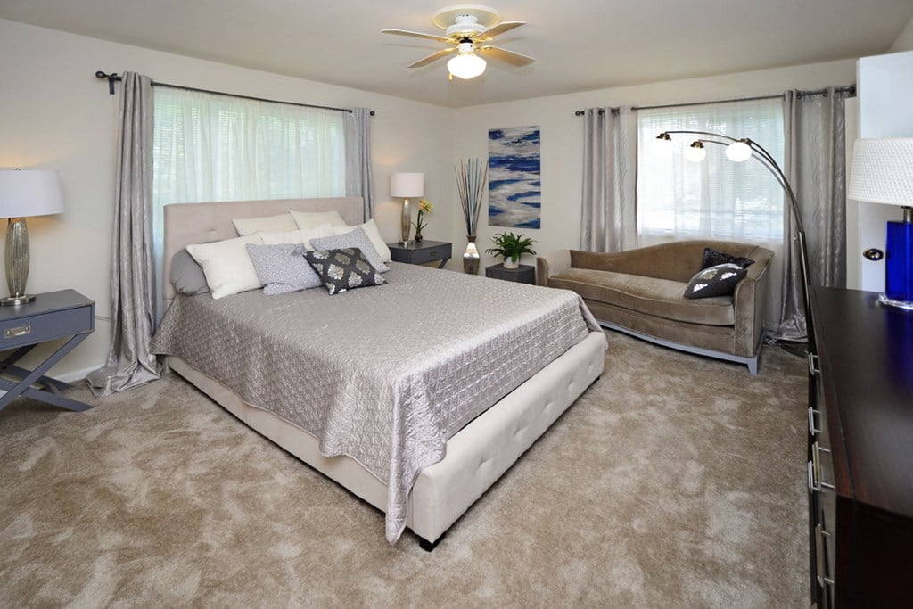 a bedroom with a bed and a couch and a ceiling fan
