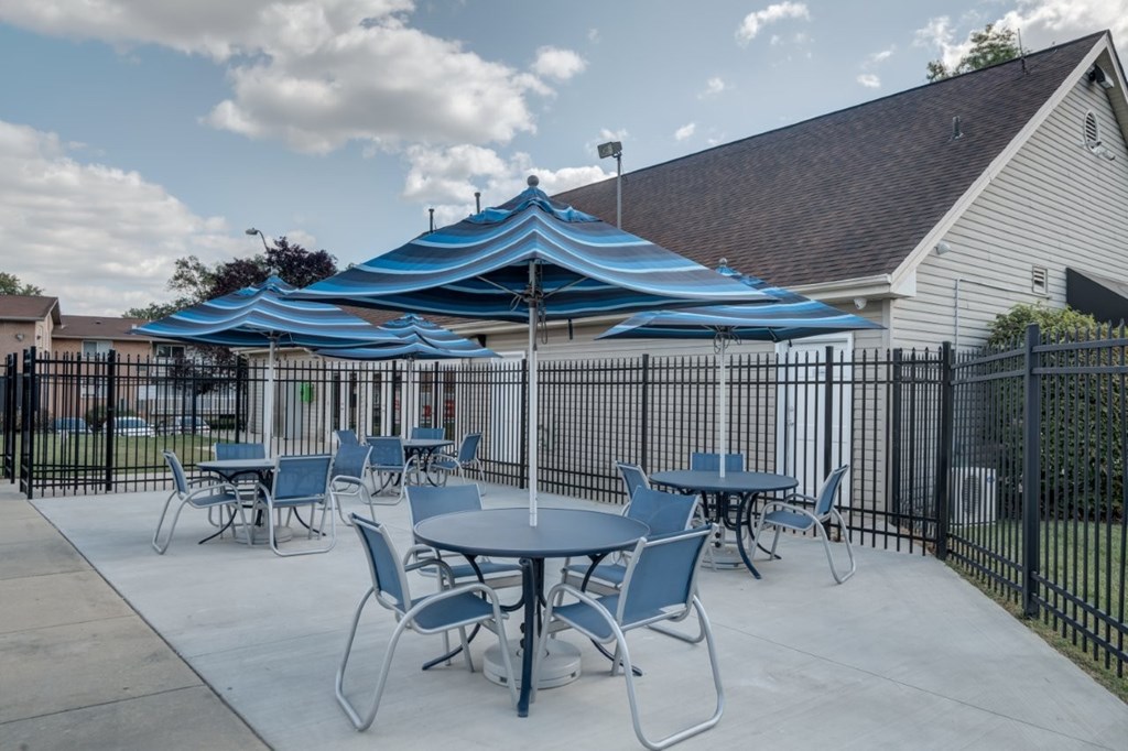 A patio with tables and chairs under a blue canopy.