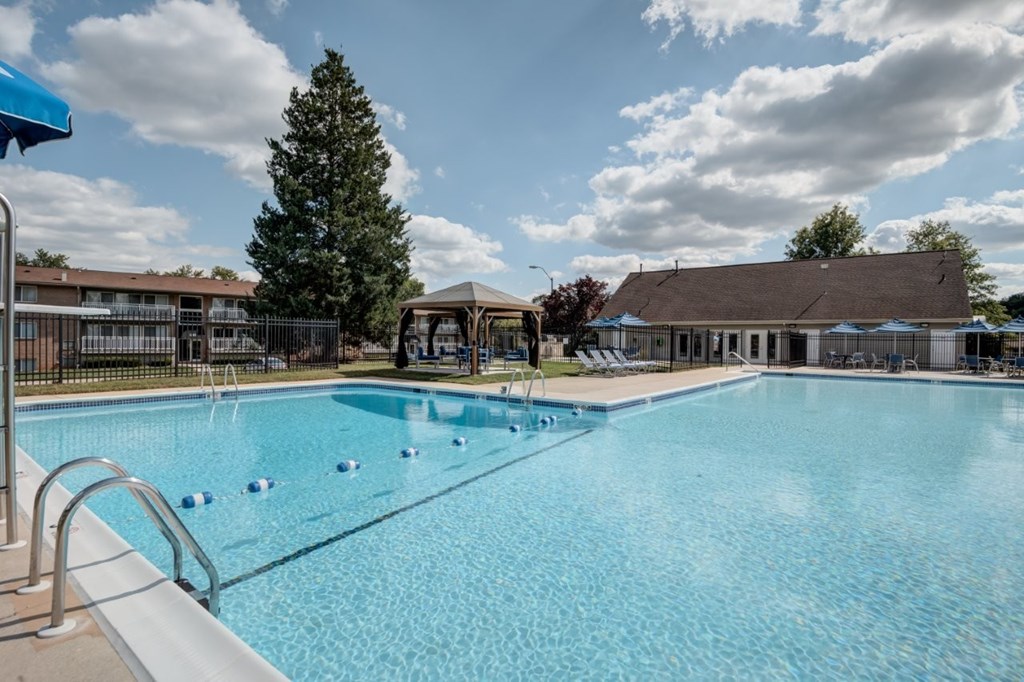 A large swimming pool with a blue sky and clouds in the background.