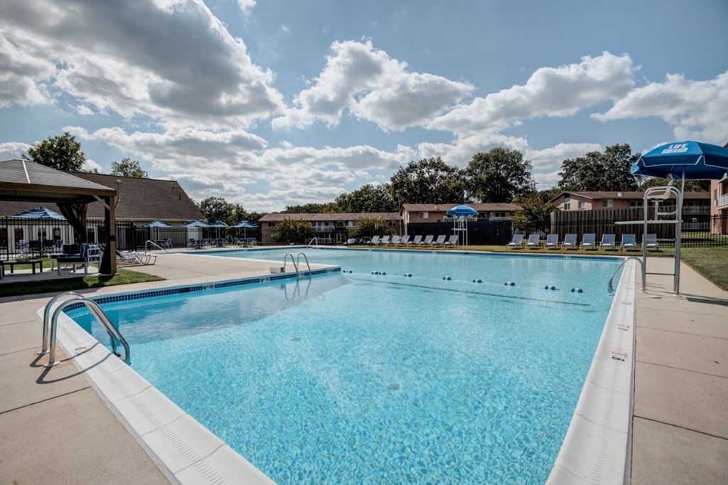 A large outdoor swimming pool with a blue sky and clouds in the background.