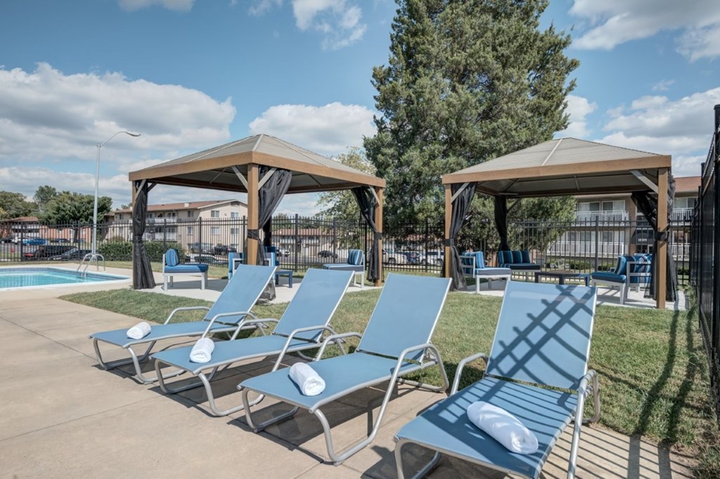 A row of blue lounge chairs are arranged in front of a pool.