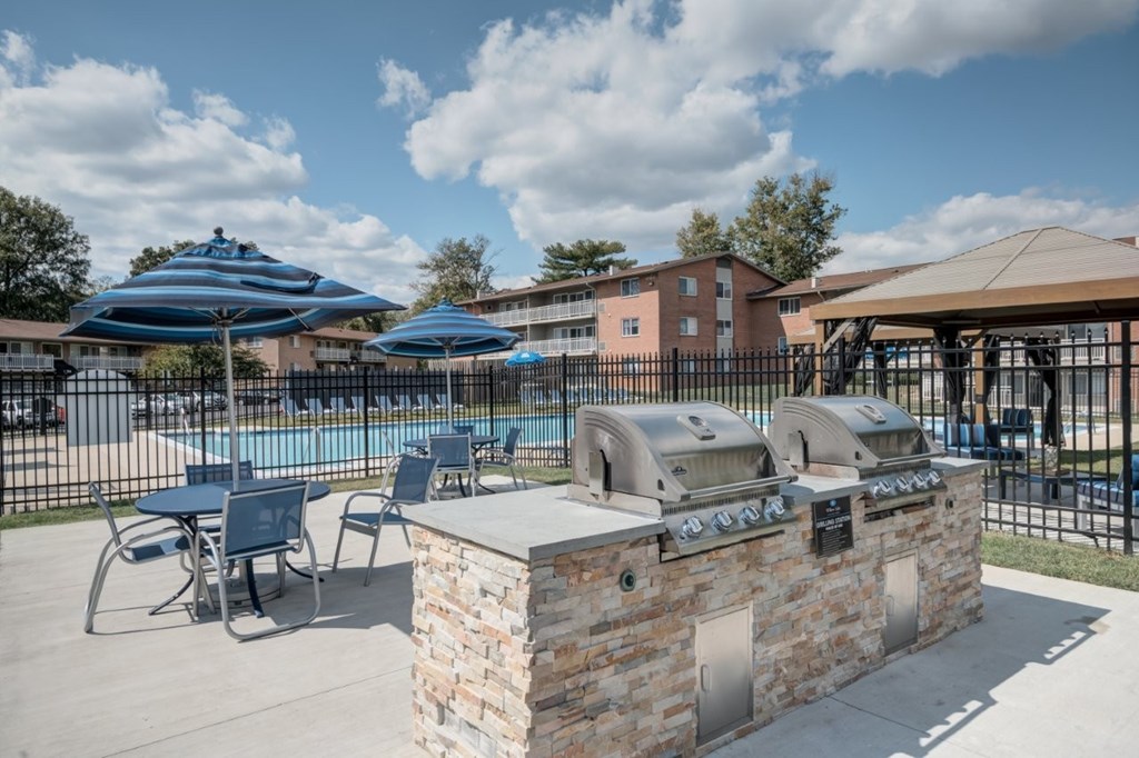 A sunny day at the pool with a stone barrier and blue umbrellas.
