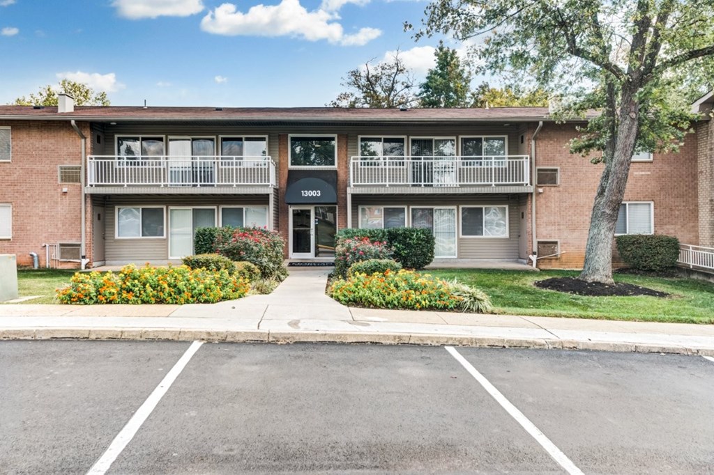 Apartment building with a parking lot in front.