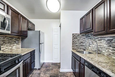 A kitchen with dark brown cabinets and a granite countertop.