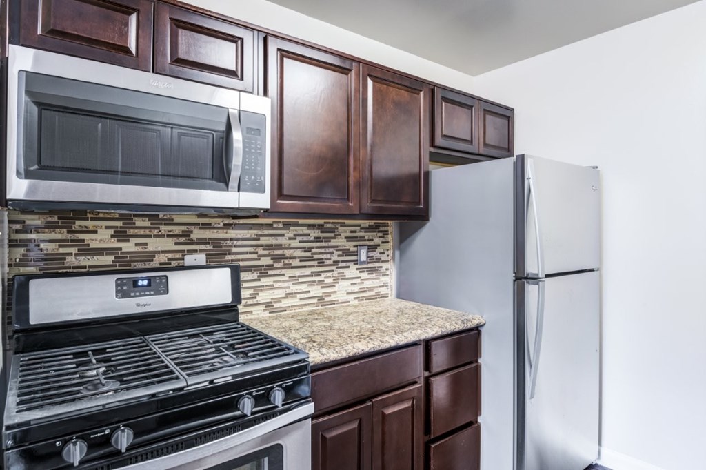 A kitchen with a stove, microwave, and refrigerator.