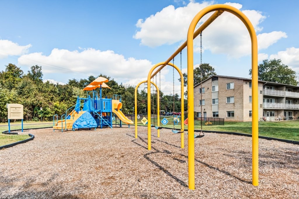 A playground with a blue slide and yellow monkey bars.