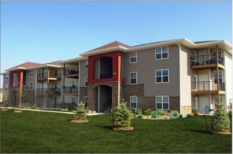 an apartment building with a green yard in front of it