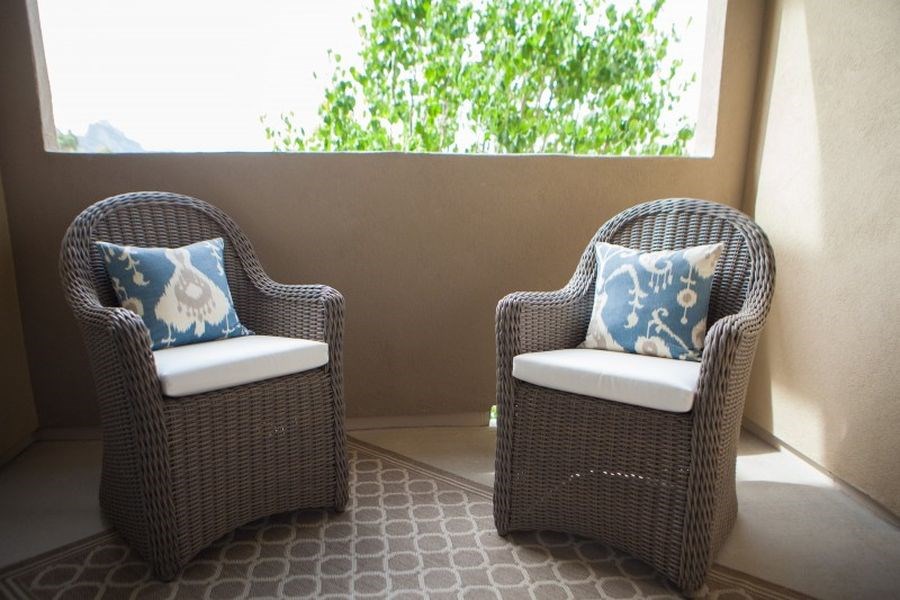 two wicker chairs with blue and white pillows on a balcony