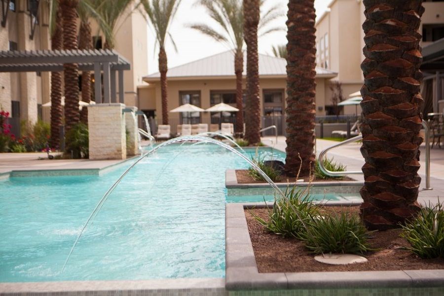 a swimming pool with water coming out of it and palm trees