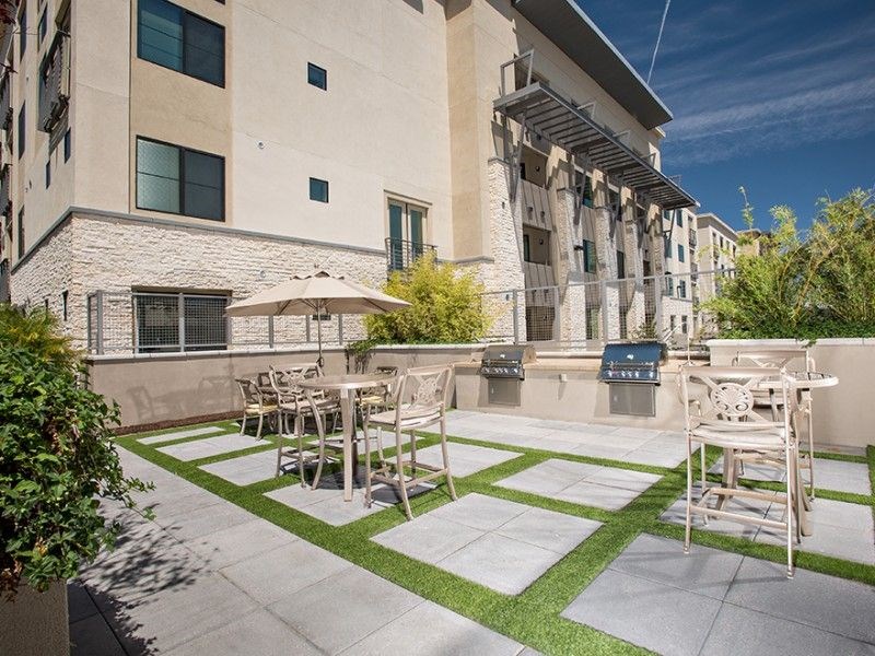 a patio with tables and chairs in front of an apartment building