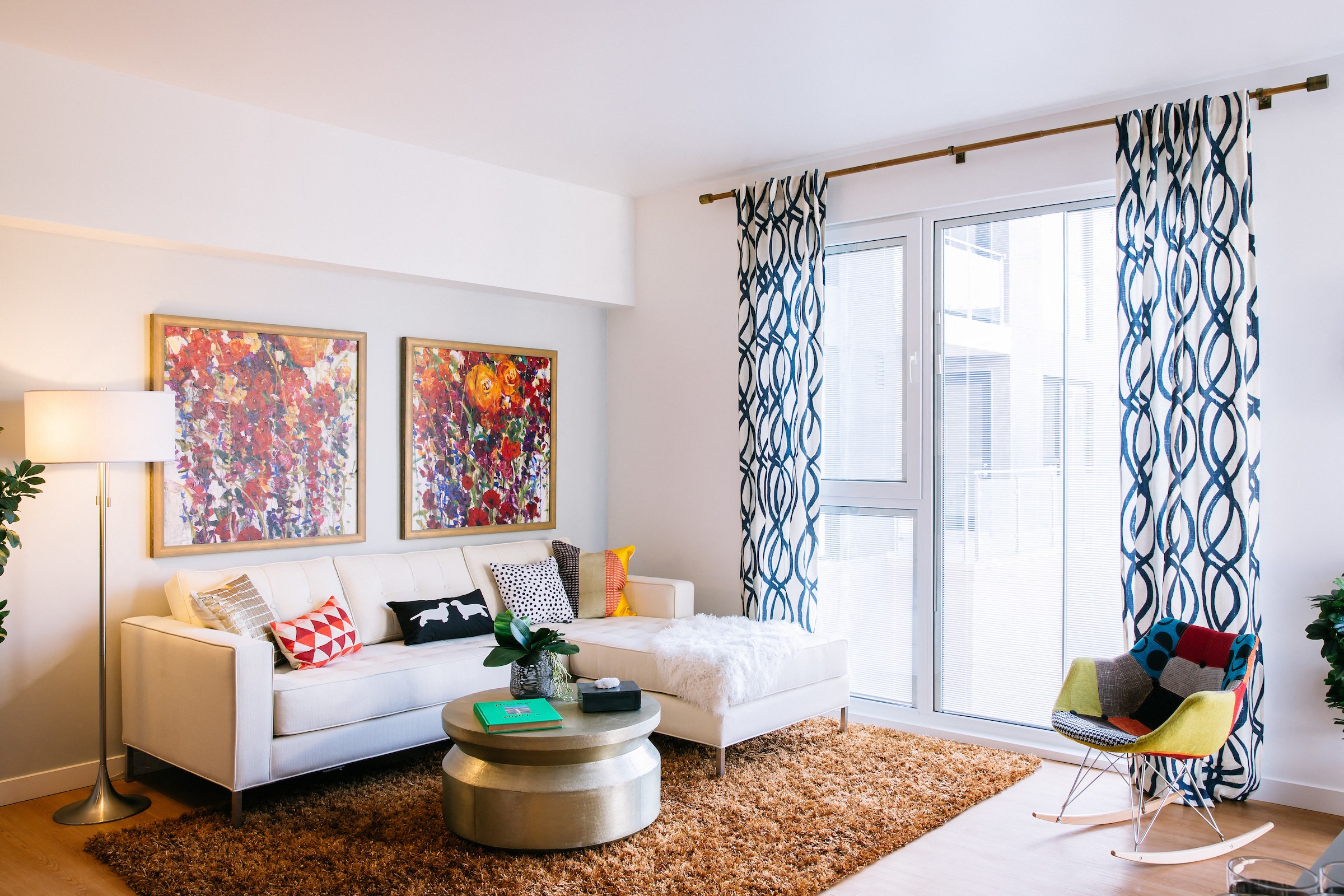 A living room with a white couch, a coffee table, and two paintings on the wall.