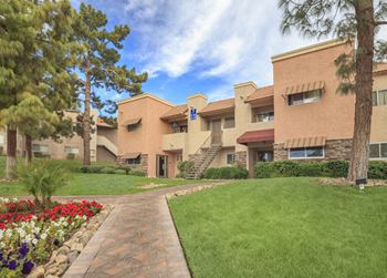 a building with a green lawn and flowers in front of it at Desert Bay Apartments, Laughlin