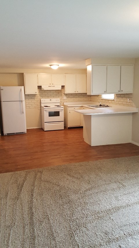 an empty kitchen with white appliances and white cabinets