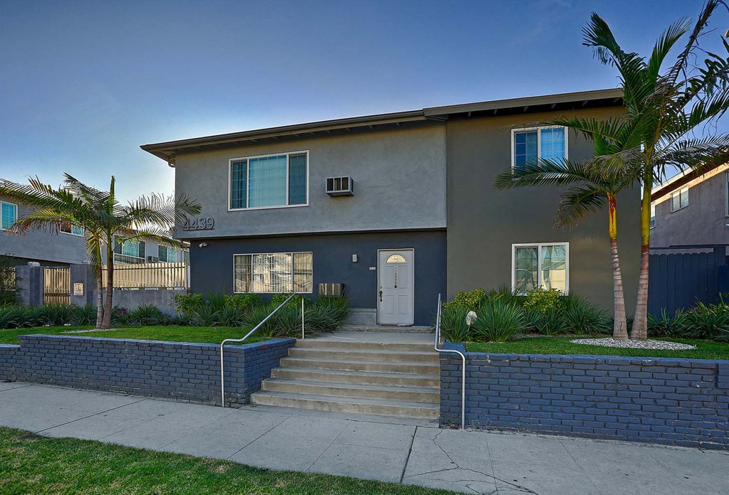 a house with stairs and palm trees in front of it