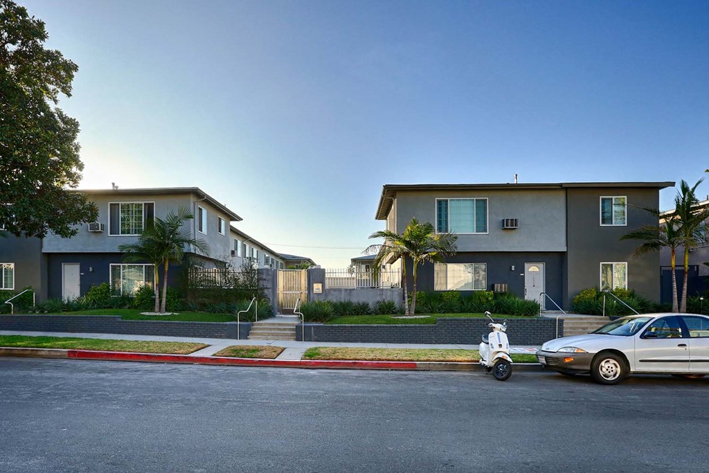 a car and a scooter parked on a street in front of houses
