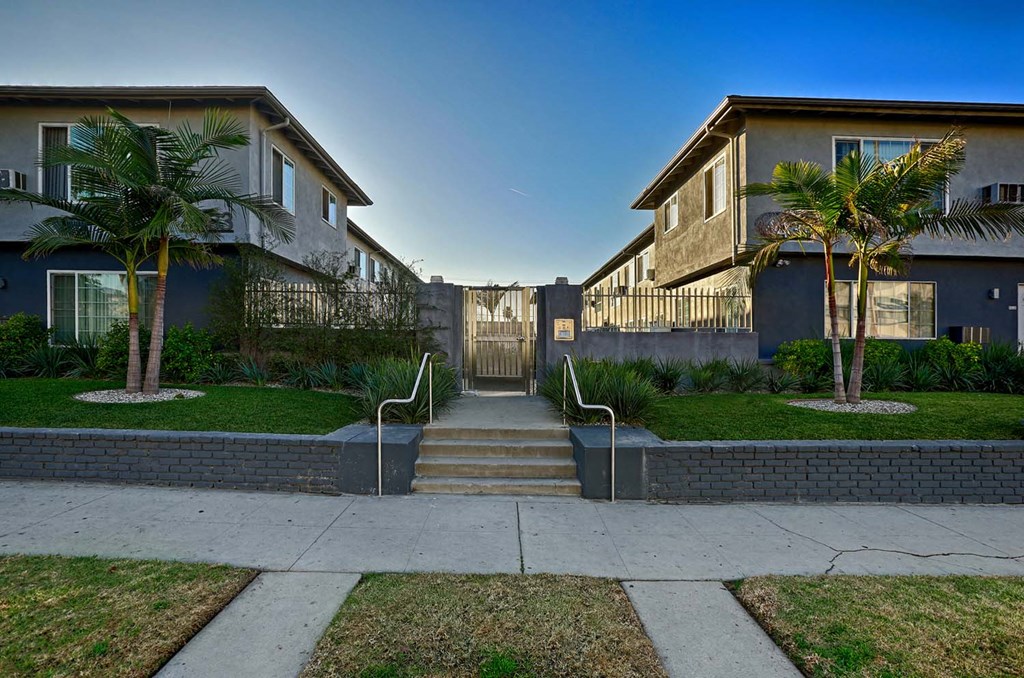 a pathway between two houses with stairs and palm trees