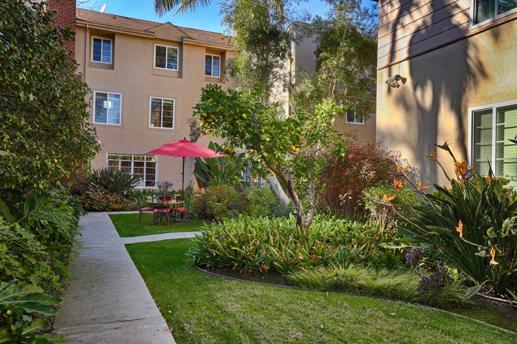 a walkway through a garden in front of an apartment building