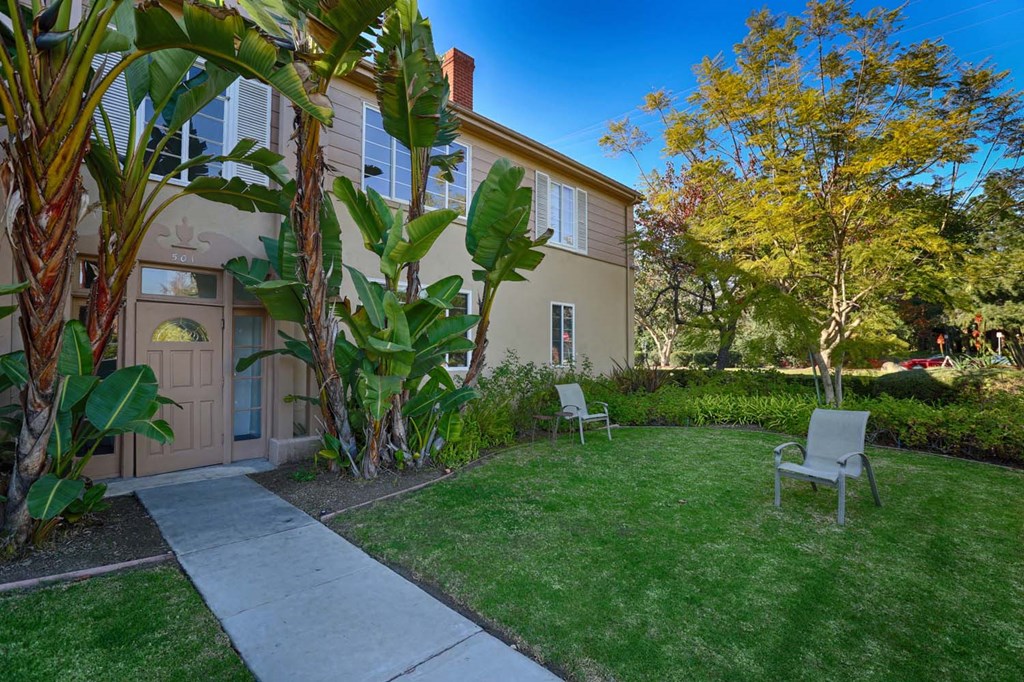 a yard with two chairs in front of a house