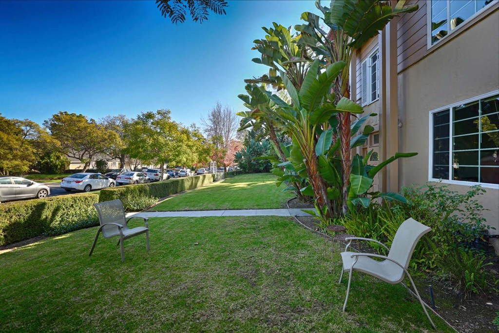 a yard with two chairs in front of a house