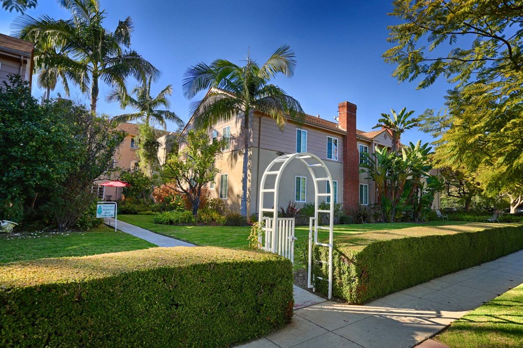 the front of a house with a garden and a white gate
