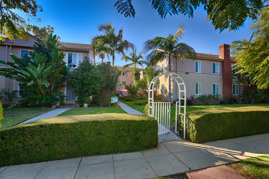 a house with a white gate and a sidewalk in front of it