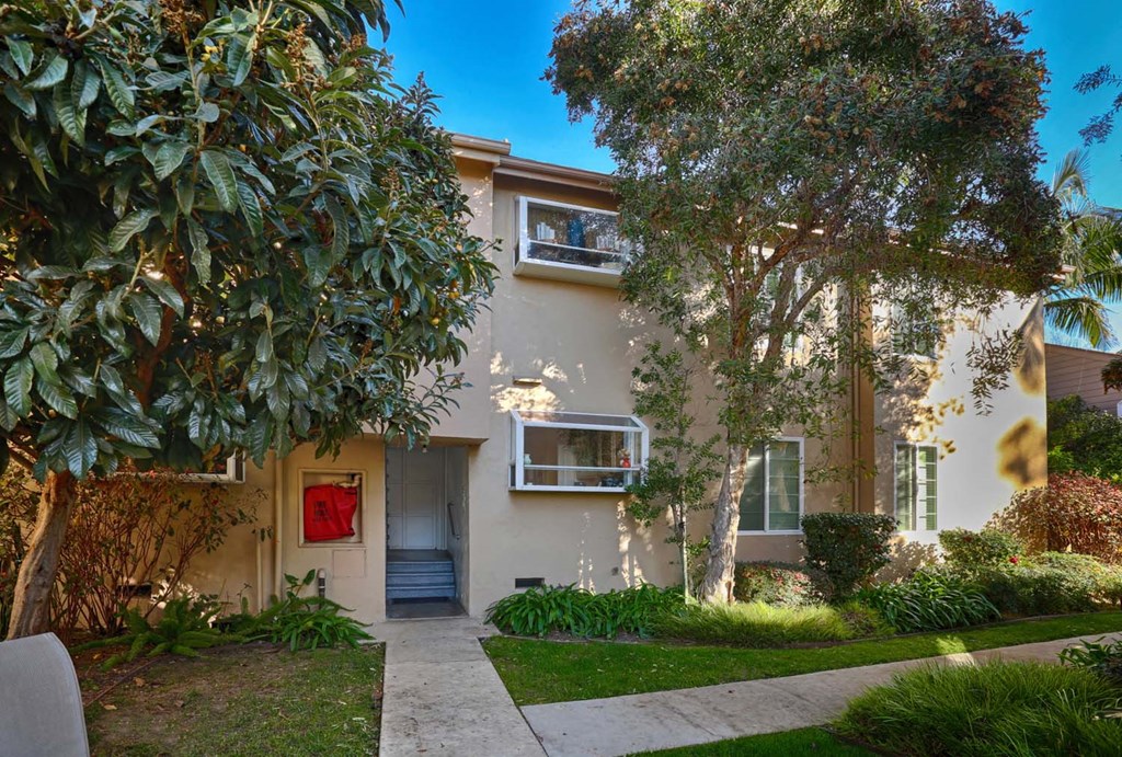 the front of a house with a sidewalk and trees