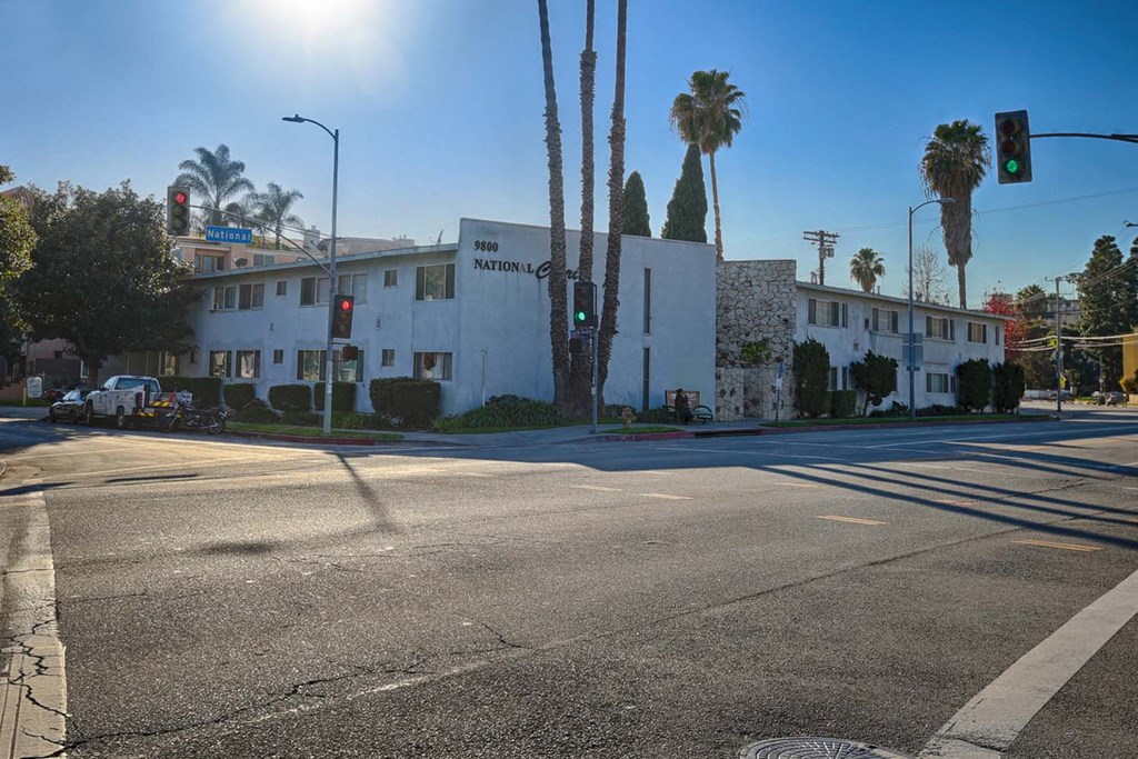 an intersection with a white building and palm trees