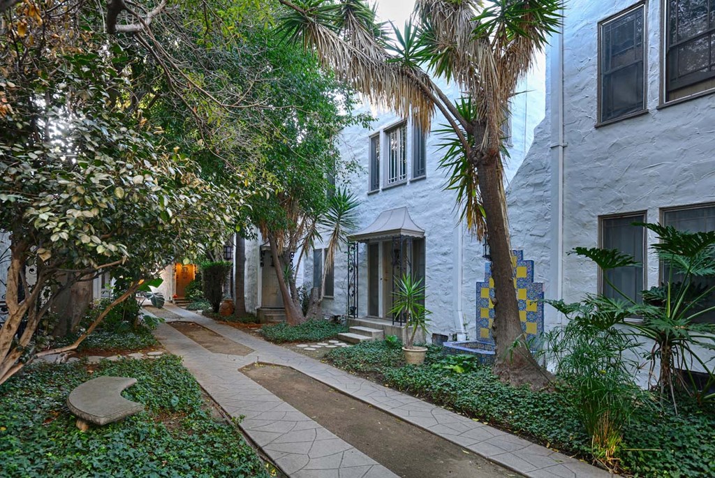 a city street with palm trees and a white building