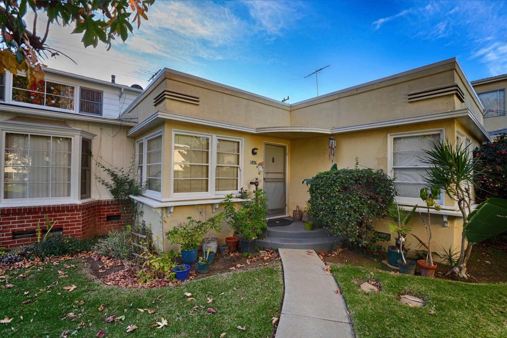 the front of a yellow house with a sidewalk in front of it
