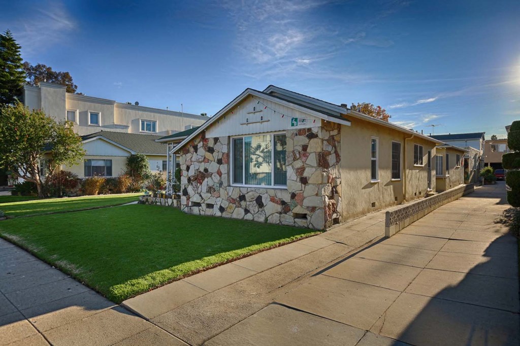 a stone house with green grass and a sidewalk