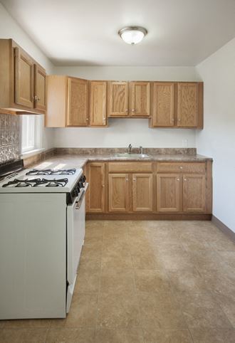 an empty kitchen with white appliances and wooden cabinets