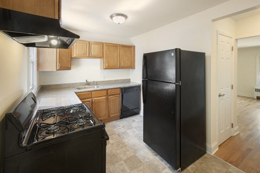 an empty kitchen with black appliances and wooden cabinets